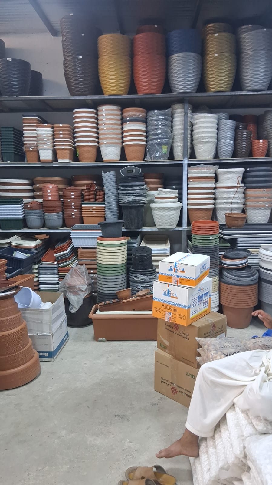مستودع أصص وأحواض زراعية بأشكال ومقاسات مختلفة على أرفف